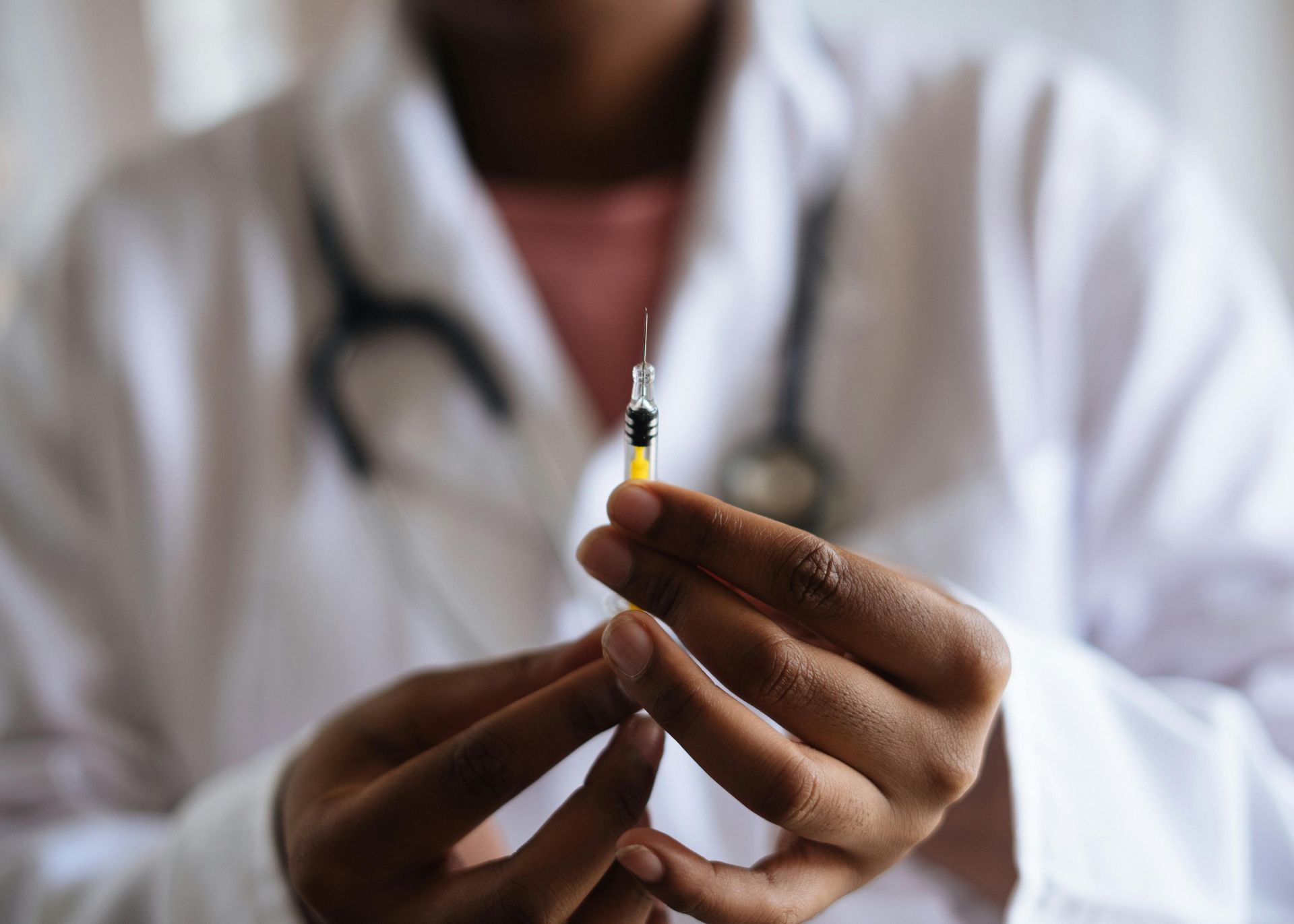 Un profesional de la salud con bata blanca sosteniendo una jeringa pequeña